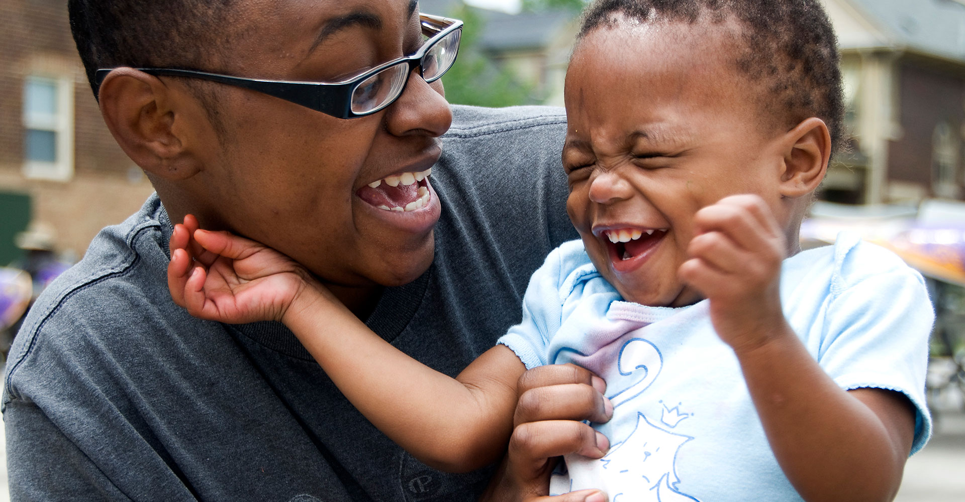 Mother and child laughing together outside their home