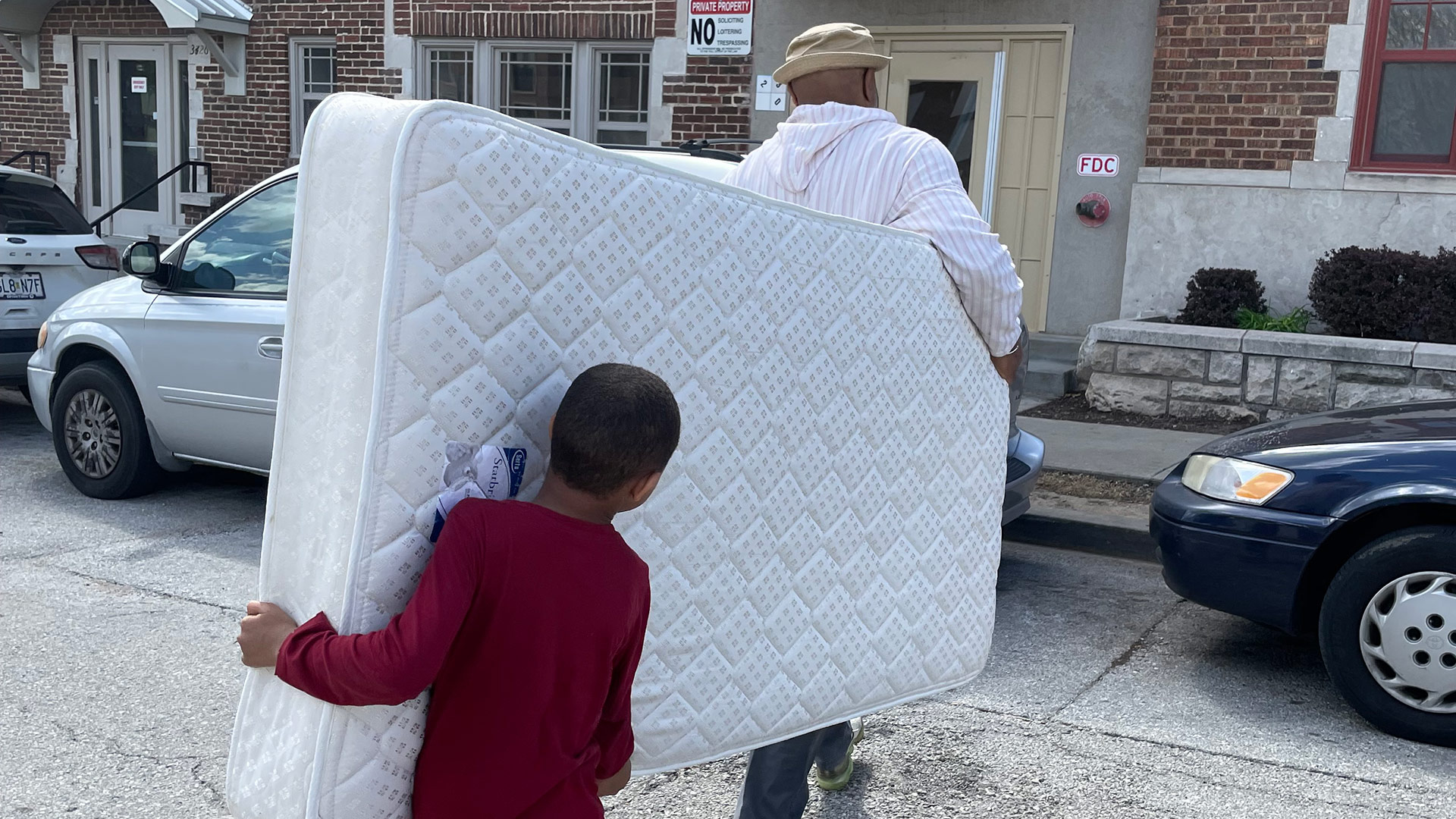 Volunteers carrying a donated mattress to help support a household