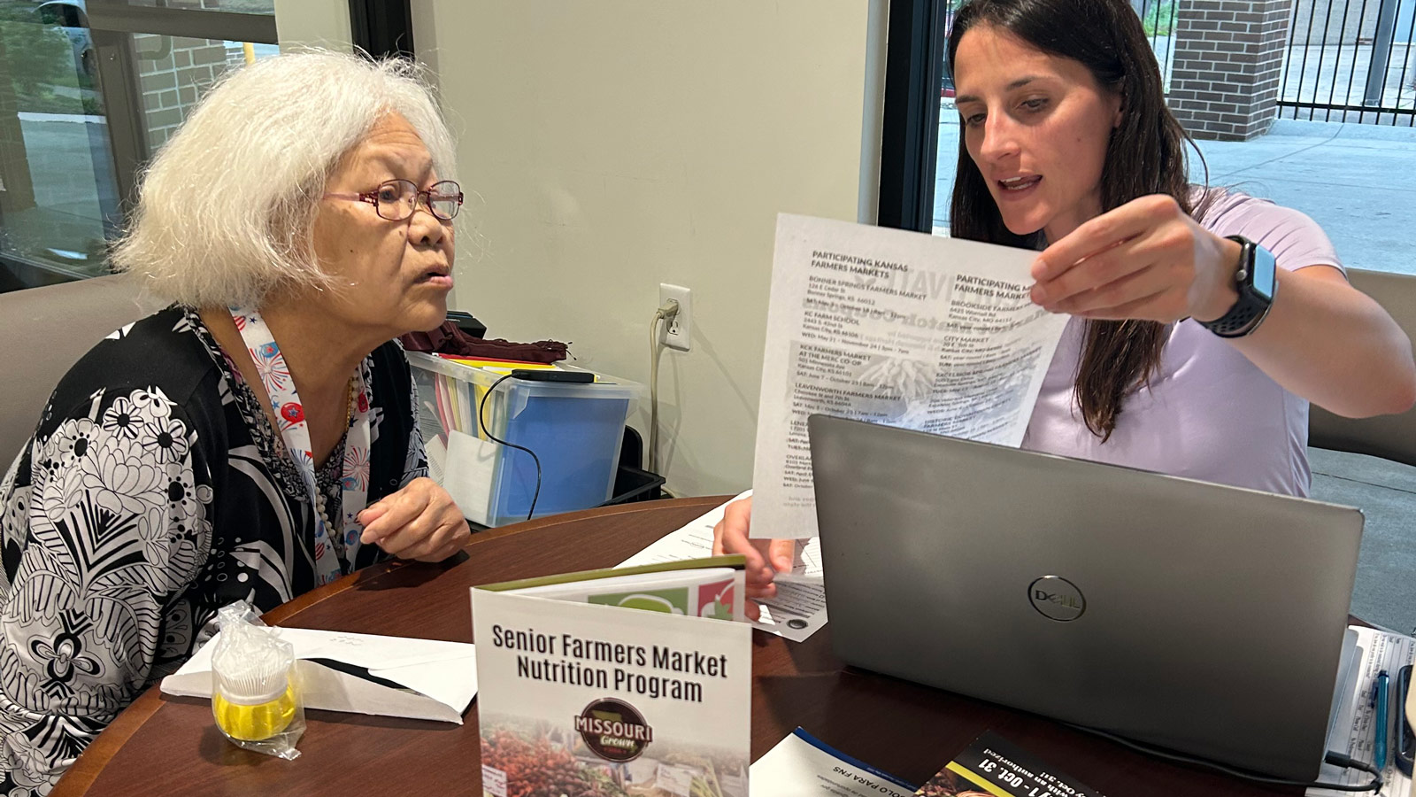 Phoenix Family staff member helping an older adult review information at a table