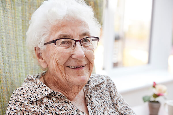 Picture of a caucasian older female sitting in front of her window