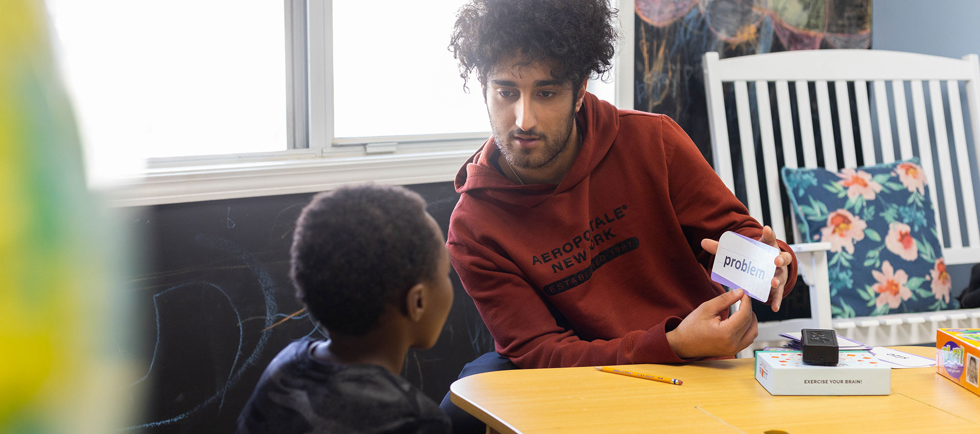 A volunteer reading with a child at a table.